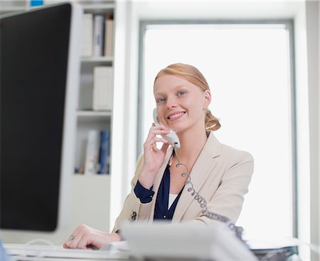 Portrait of confident businesswoman using computer and talking on telephone Stock Photo - Premium Royalty-Free, Code: 6113-06498862