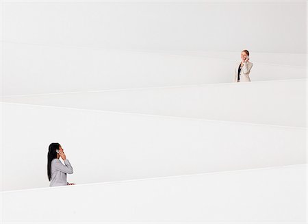 Businesswomen talking on cell phones on modern staircase Stock Photo - Premium Royalty-Free, Code: 6113-06498878