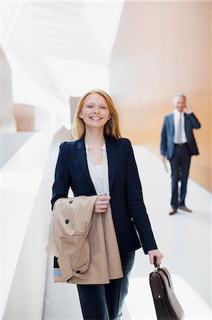 photographs of women walking away - Portrait of smiling businesswoman with coat and briefcase Stock Photo - Premium Royalty-Free, Code: 6113-06498800