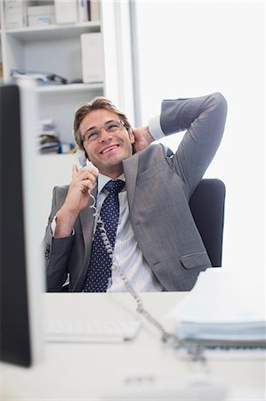 simsearch:6113-06498879,k - Smiling businessman talking on telephone at desk in office Fotografie stock - Premium Royalty-Free, Codice: 6113-06498805