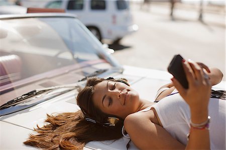 Woman listening to mp3 player on convertible Foto de stock - Sin royalties Premium, Código: 6113-06498971