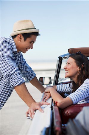 retro woman flirting - Smiling couple talking in convertible Stock Photo - Premium Royalty-Free, Code: 6113-06498921