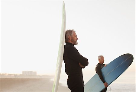 picture of a middle aged man on a surf board - Older surfer leaning on board on beach Stock Photo - Premium Royalty-Free, Code: 6113-06499052