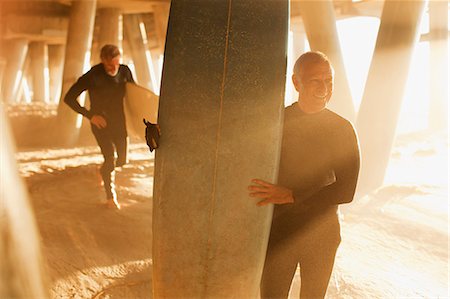 seniors surfing - Older surfers carrying boards under pier Stock Photo - Premium Royalty-Free, Code: 6113-06499066