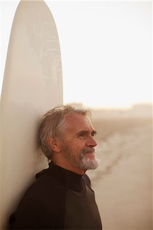 Older surfer leaning on board on beach Stock Photo - Premium Royalty-Free, Code: 6113-06499069
