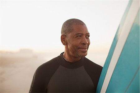 Older surfer carrying board on beach Stock Photo - Premium Royalty-Free, Code: 6113-06499078