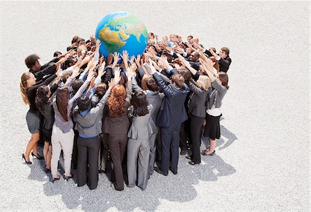 people on the globe - Crowd of business people in huddle reaching for globe Stock Photo - Premium Royalty-Free, Code: 6113-06499150