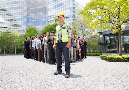 stand out from the crowd - Portrait of smiling construction worker with business people in background Stock Photo - Premium Royalty-Free, Code: 6113-06499172