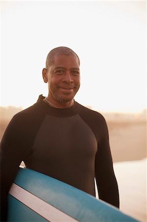 Older surfer carrying board on beach Stock Photo - Premium Royalty-Free, Code: 6113-06499108