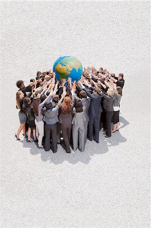 simsearch:6113-06499214,k - Crowd of business people in huddle lifting globe overhead Stock Photo - Premium Royalty-Free, Code: 6113-06499213