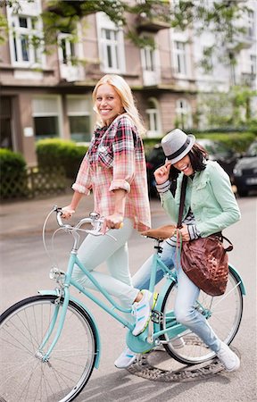 passageira - Women riding bicycle together on city street Foto de stock - Royalty Free Premium, Número: 6113-06625559