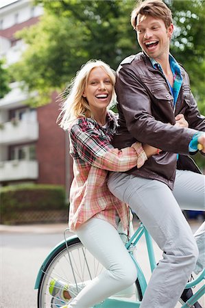 Couple riding bicycle together on city street Stock Photo - Premium Royalty-Free, Code: 6113-06625578