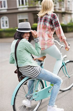 Women riding bicycle together on city street Stock Photo - Premium Royalty-Free, Code: 6113-06625587