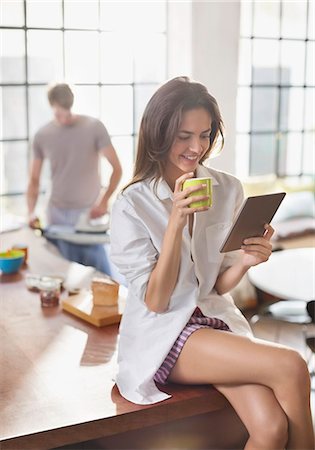 drinking sitting - Woman using digital tablet in kitchen Stock Photo - Premium Royalty-Free, Code: 6113-06625589