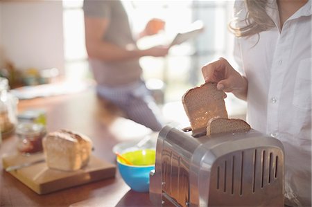 pan tostado - Woman putting bread in toaster Foto de stock - Sin royalties Premium, Código: 6113-06625620