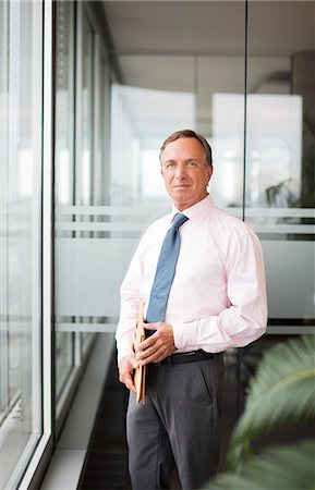 Businessman standing at office window Foto de stock - Sin royalties Premium, Código: 6113-06625724