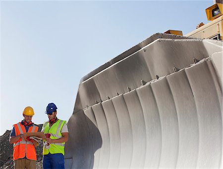 Workers reading blueprints by digger in quarry Stock Photo - Premium Royalty-Free, Code: 6113-06625846