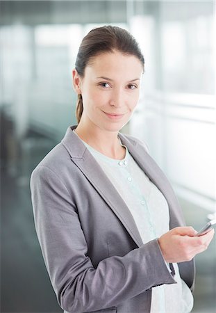 Businesswoman using cell phone in office Stock Photo - Premium Royalty-Free, Code: 6113-06625800