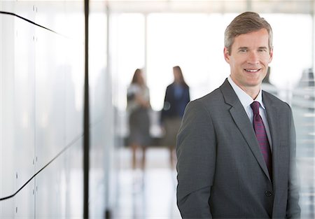 Businessman smiling in office hallway Stock Photo - Premium Royalty-Free, Code: 6113-06625838