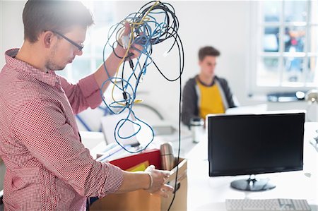 Businessman untangling cords in office Stock Photo - Premium Royalty-Free, Code: 6113-06626047