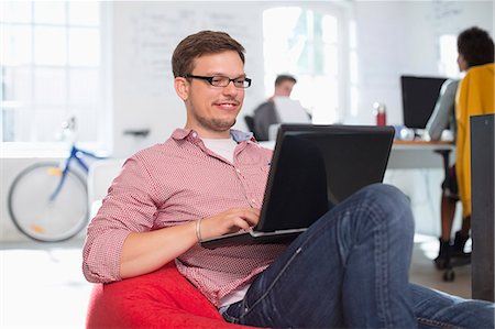 simsearch:6113-06626056,k - Businessman using laptop in bean bag chair in office Stock Photo - Premium Royalty-Free, Code: 6113-06626045