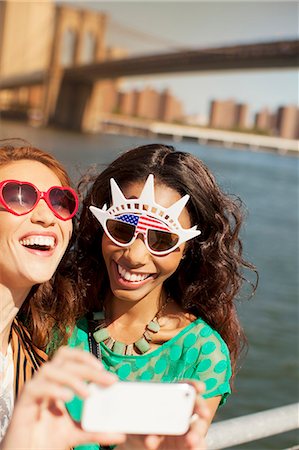 simsearch:6113-06626186,k - Women in novelty sunglasses taking picture by city cityscape Stock Photo - Premium Royalty-Free, Code: 6113-06626151