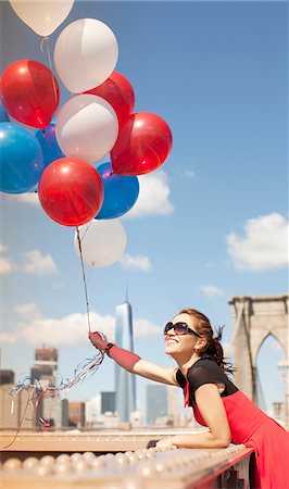 Woman holding bunch of balloons on urban bridge Stock Photo - Premium Royalty-Free, Code: 6113-06626111