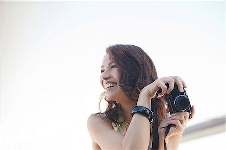 people looking up at camera - Smiling woman taking pictures outdoors Stock Photo - Premium Royalty-Free, Code: 6113-06626128