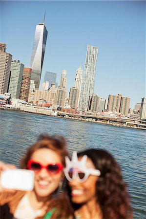 simsearch:6113-06626132,k - Women in novelty sunglasses taking picture by city cityscape Photographie de stock - Premium Libres de Droits, Code: 6113-06626139