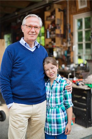 portrait man senior 70 years old casual clothes not asian not hispanic - Man and granddaughter smiling in garage Stock Photo - Premium Royalty-Free, Code: 6113-06626366