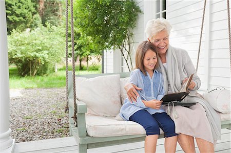 pictures of older adults sitting on porch swing - Woman and granddaughter reading on porch swing Stock Photo - Premium Royalty-Free, Code: 6113-06626338