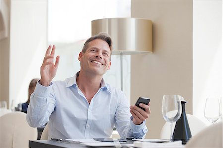 Businessman using cell phone in restaurant Stock Photo - Premium Royalty-Free, Code: 6113-06626579