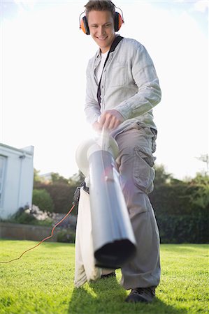 Man blowing leaves in backyard Stock Photo - Premium Royalty-Free, Code: 6113-06753245