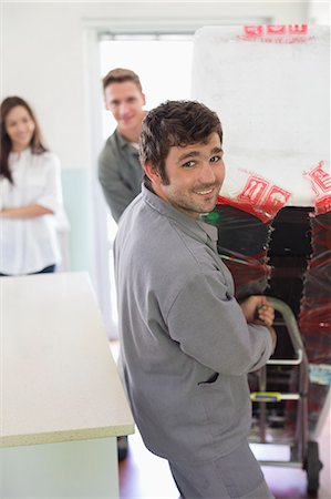 Worker wheeling appliance in kitchen Foto de stock - Royalty Free Premium, Número: 6113-06753278