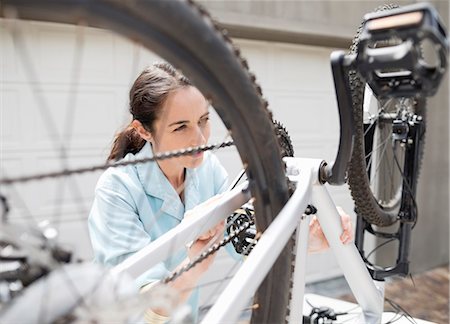 Woman working on bicycle in driveway Stock Photo - Premium Royalty-Free, Code: 6113-06753291