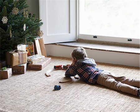 relaxing christmas - Boy playing with trains by Christmas tree Stock Photo - Premium Royalty-Free, Code: 6113-06753360