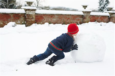 playing outdoor snow - Boy making snowman outdoors Stock Photo - Premium Royalty-Free, Code: 6113-06753361