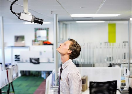 people looking up at camera - Businessman examining security camera in office Stock Photo - Premium Royalty-Free, Code: 6113-06753445