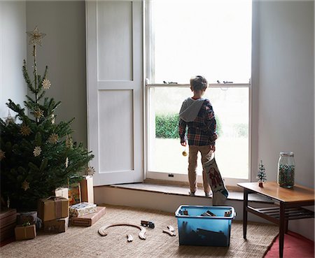 standing at window - Boy holding Christmas stocking at window Stock Photo - Premium Royalty-Free, Code: 6113-06753402