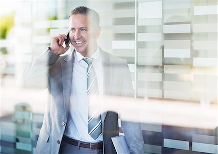 standing at window - Businessman talking on cell phone Stock Photo - Premium Royalty-Free, Code: 6113-06753506