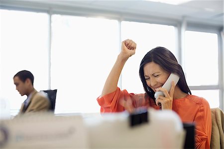 Businesswoman cheering at desk in office Foto de stock - Sin royalties Premium, Código: 6113-06753522