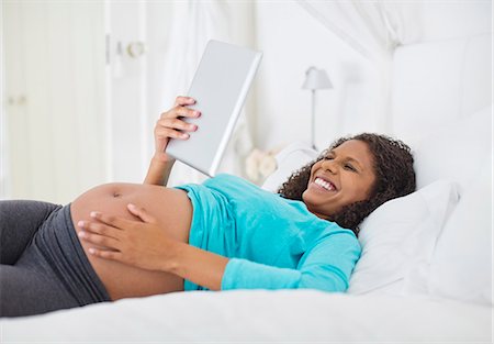 Pregnant woman using tablet computer on bed Stock Photo - Premium Royalty-Free, Code: 6113-06753605
