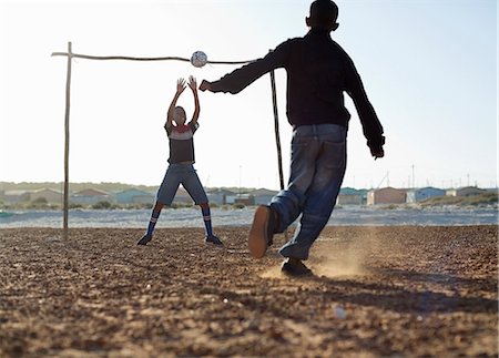 simsearch:6113-06753787,k - Boys playing soccer together in dirt field Photographie de stock - Premium Libres de Droits, Code: 6113-06753766