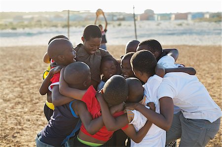 simsearch:6113-06753824,k - Boys huddled together in dirt field Stock Photo - Premium Royalty-Free, Code: 6113-06753792