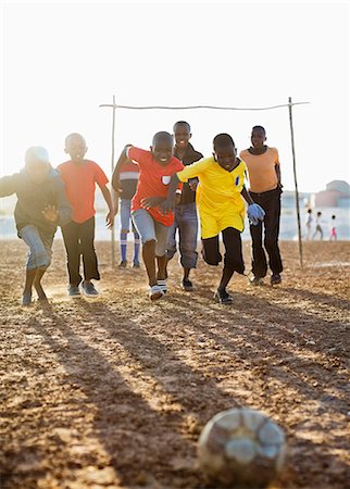 simsearch:6113-07159183,k - Boys playing soccer together in dirt field Stock Photo - Premium Royalty-Free, Code: 6113-06753798