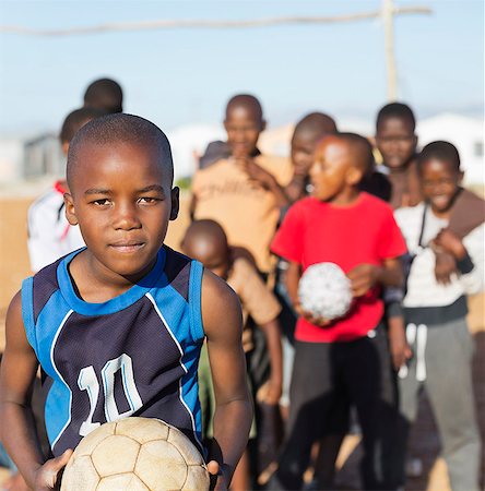 Boys holding soccer balls in dirt field Stock Photo - Premium Royalty-Free, Code: 6113-06753810