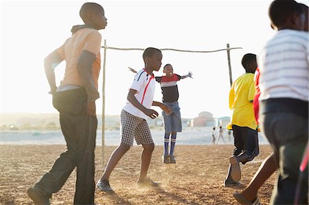 simsearch:6113-06753807,k - Boys playing soccer together in dirt field Stock Photo - Premium Royalty-Free, Code: 6113-06753819