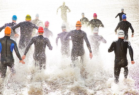 Triathletes in wetsuits running into ocean Stock Photo - Premium Royalty-Free, Image code: 6113-06753961