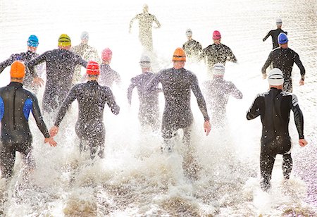 Triathletes in wetsuits running into ocean Foto de stock - Sin royalties Premium, Código: 6113-06753961