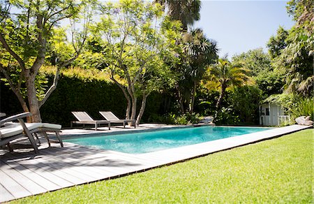 piscina natural - Lawn chairs and swimming pool in backyard Foto de stock - Royalty Free Premium, Número: 6113-06753937